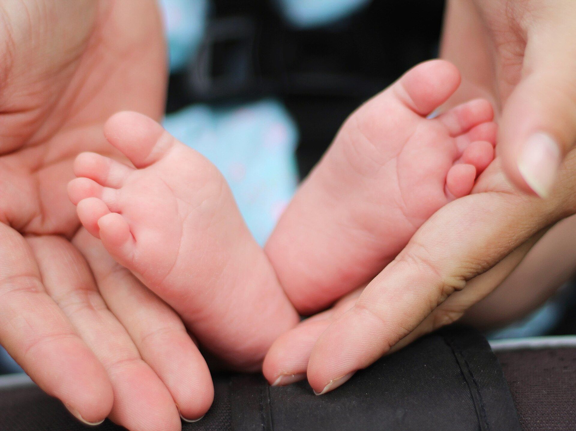 Les mains d'une mère tiennent délicatement les pieds de son nouveau-né.